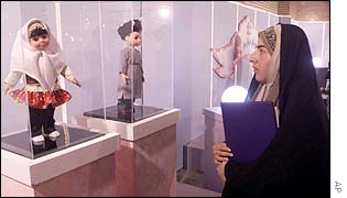 An Iranian woman looks at the Sara (L) and Dara dolls
