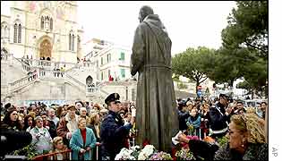 Police and crowds gather round the 'weeping' statue of Padre Pio