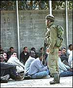 Israeli soldier stands guard over Palestinian men rounded up in Tulkarm