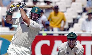 South African batsman Graeme Smith plays a straight drive, watched by Australian wicket-keeper Adam Gilchrist