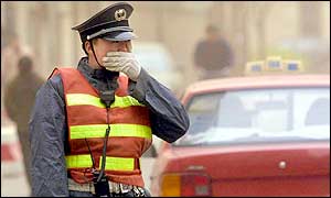 A security guard covers his face with his hand as he stands watch at a street junction in Beijing