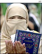 Pakistani woman holds the Koran and prays for victory