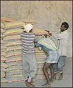 Men move bags of cement at a warehouse for a pittance