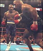 Evander Holyfield pours forward as Mike Tyson stumbles to the ropes