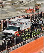 An ambulance with an empty stretcher symbolizing all who perished but were not found at the World Trade Center leaves the site past an honour guard 