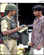 An Indian security guard checks a man's papers in Srinagar