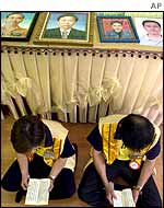 Photographs of victims rest behind volunteers reading scriptures