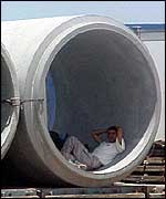 Man shelters from sun in concrete pipe