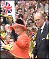 The Queen and Prince Philip wave as their carriage is driven through the crowds