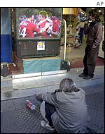 A homeless man watches the game on a shop TV