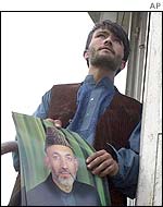Supporter of interim Afghan leader Hamid Karzai putting up a poster