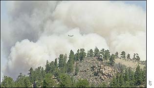 A slurry bomber is dwarfed by huge smoke clouds above the Hayman forest fire north of county road 77 outside Lake George in the Pike National Forest