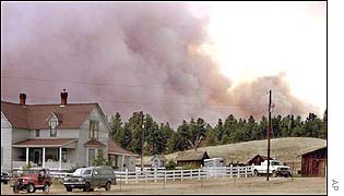 Fire and smoke loom rise behind the Twin Creek Ranch just north of Highway 24 in Florissant, Colorado
