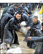 Police officers in the northwest Shaanxi province form a human chain to place sandbags in a river