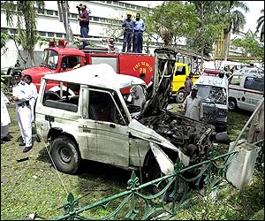 Rescue workers look at the remains of a white van - possibly the vehicle carrying the bomb 