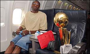 Kobe Bryant sits alongside the Larry O'Brien NBA Championship Trophy on the way back to LA from New Jersey.