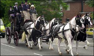 A horse drawn carriage with race goers