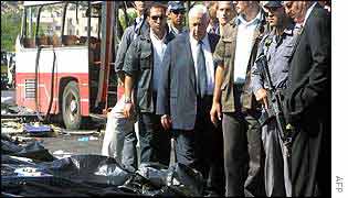 Ariel Sharon (in tie) surveys body bags at the scene