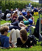 Passengers lounging around on grass at Stansted airport, Essex