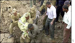 Soldiers carry a body from a wrecked house