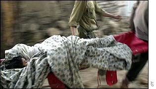 A boy is carried alive from the rubble