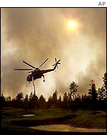 A helicopter takes water from a golf course