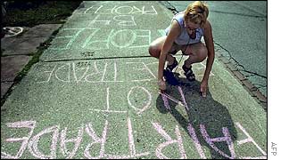 Student Karen Kaufman scrawls her anti-globalization message on a pavement during a G8 protest in Toronto