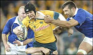 Three French tacklers try to snare Australian fly-half Stephen Larkham 