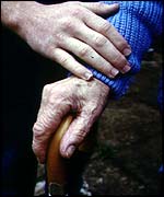 Helper with hand on old person's hand
