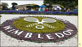 Fans continue to shelter under their umbrellas as play fails to start on time