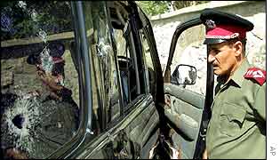 An Afghan policeman looks at the ambushed car