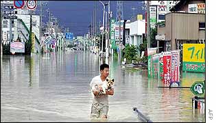 A man holds his dog on a flooded street in Oogaki, central Japan
