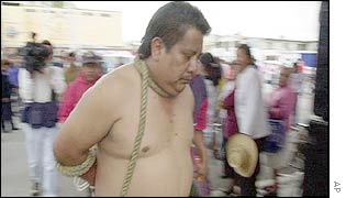 A police officer held hostage is taken away in ropes