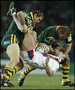 Paul Johnson is hauled to the ground by Jason Stevens and Shane Webcke