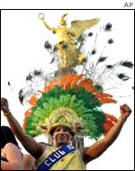 An unidentified reveller wears a Brazilian carnival costume as he dances in front of Berlin's Victory Column