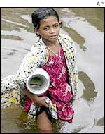 Girl wades through flooded streets looking for drinking water