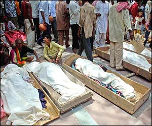 Mourning families sit by coffins holding their relatives' bodies 