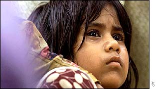 A young girl weeps as she stands near a victim's coffin