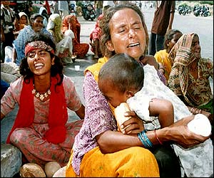 A woman cries for her dead relatives as she holds on to her baby