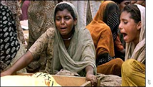 Two woman weep over the open coffin of a family member