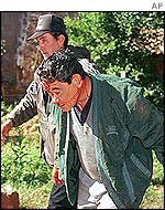 A man is led away by a police officer in Ita