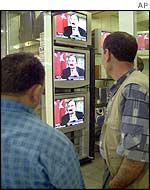 Turkish men watch television at an electronics market in Istanbul as Turkey's ailing Prime Minister Bulent Ecevit gives a TV interview 