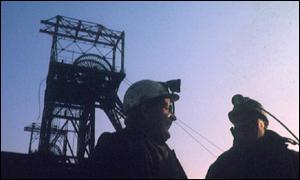 shadow of miners under a pit head