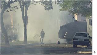 A police officer runs through tear gas in front of the Parliament Building during the riots in Asuncion on Monday