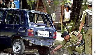 Indian forces examine a car after a blast at an Indian base in Kashmir