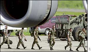 US troops walk under the engine of a plane that will take them out of the Philippines