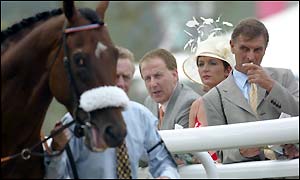 Racegoers work out their bets by the paddock at Goodwood