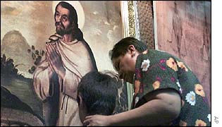 Mexican woman and child in front of portrait of Juan Diego