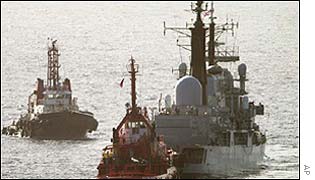HMS Nottingham flanked by tugs