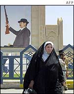 A woman walks by a Saddam Hussein poster in Baghdad